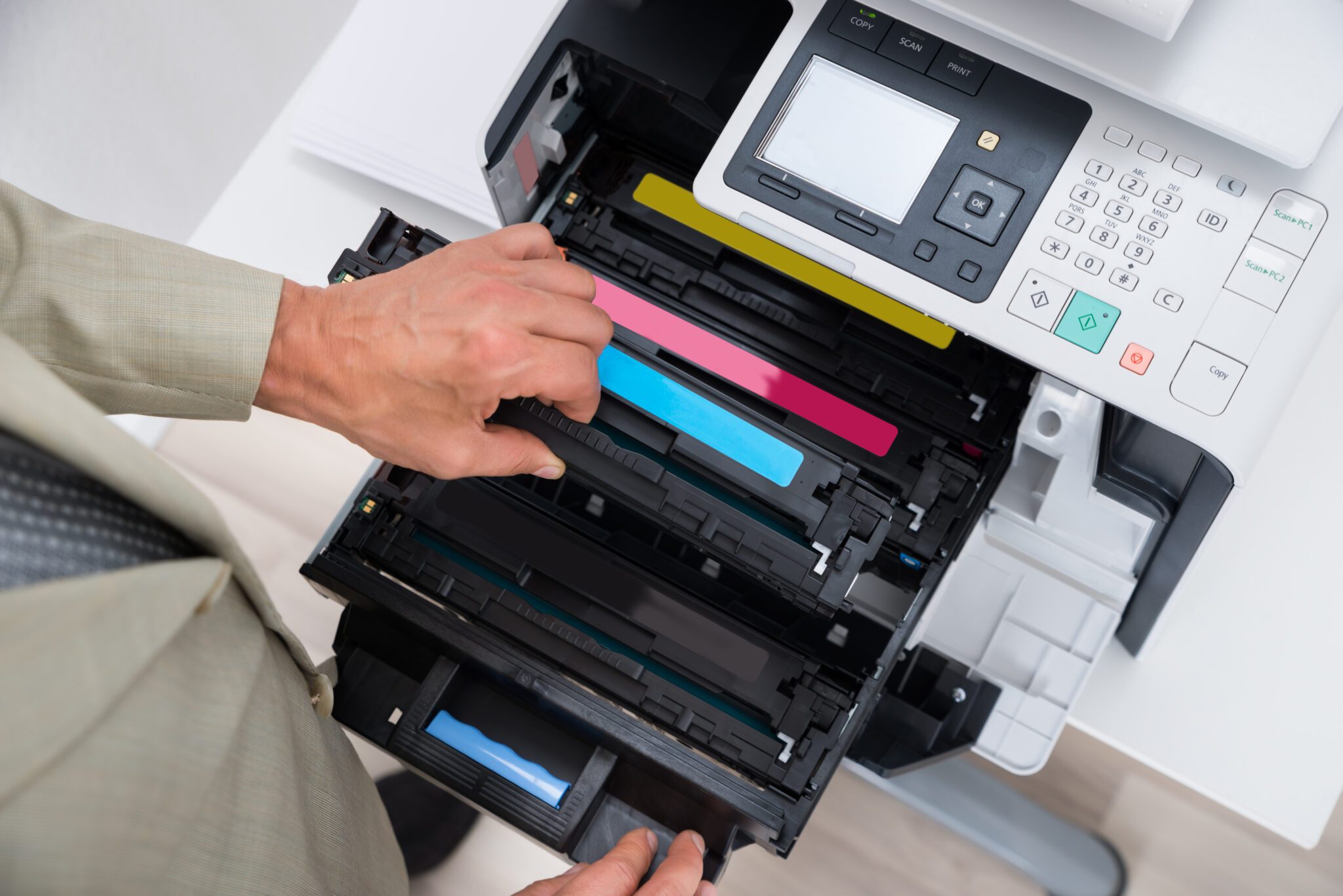 A person changing a cyan toner cartridge in a printer.
