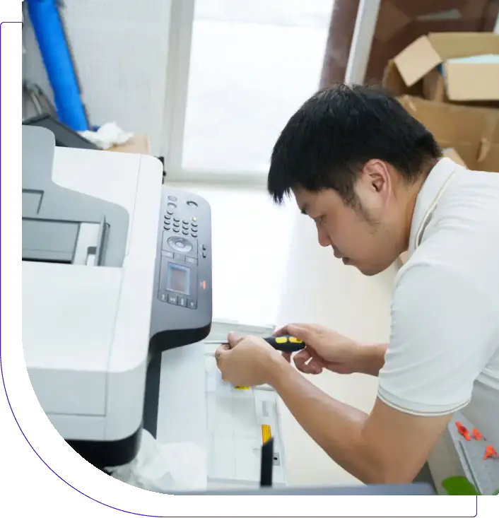 Man repairing a printer in an office.