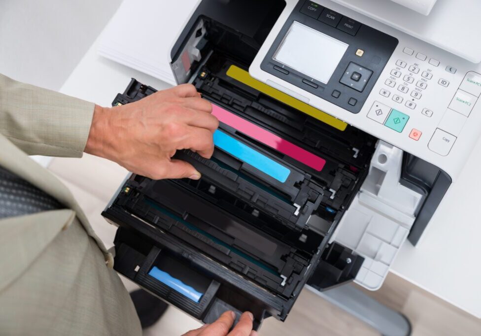 A person changing a cyan toner cartridge in a printer.